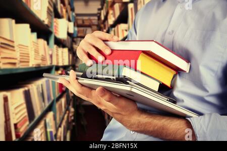 Student holding books and laptop in library Stock Photo