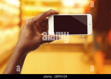 Mans hand shows mobile smart phone, blurred background Stock Photo