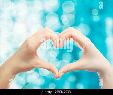 Female hands in shape of heart, on blurred background Stock Photo