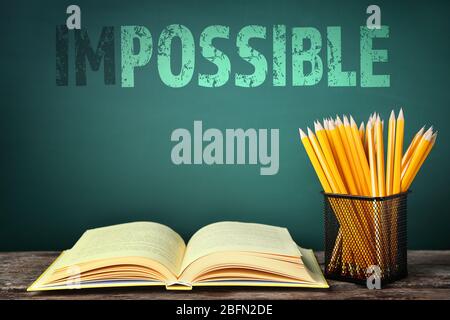 Word impossible transformed into possible on blackboard and school supplies Stock Photo