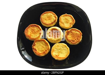 Delicious rosy fried cheesecakes on a dark dish, isolated on a white background. Stock Photo