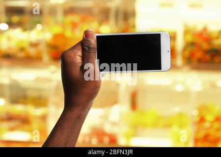 Mans hand shows mobile smart phone, blurred background Stock Photo