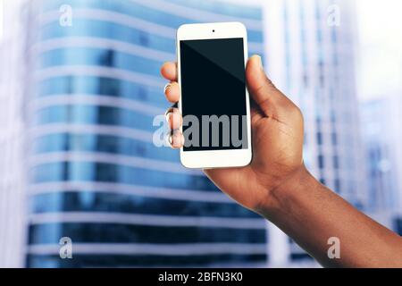 Mans hand shows mobile smart phone, blurred background Stock Photo
