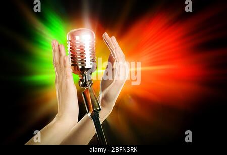 Retro microphone in female hands on laser rays background Stock Photo