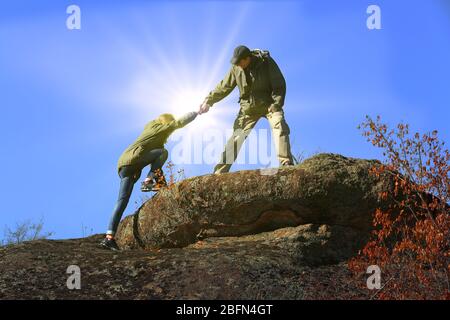 Helping hands with sunlight between two climbers Stock Photo
