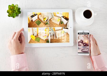 Male hands with tablet and phone on white table. Home security system concept Stock Photo