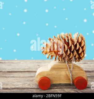 Wooden toy car carrying Christmas pine on color background Stock Photo