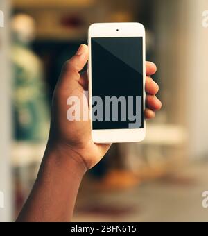 Mans hand shows mobile smart phone, blurred background Stock Photo