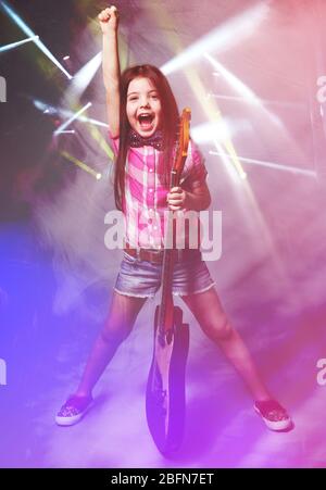 Beautiful artistic little girl playing guitar on laser rays background Stock Photo