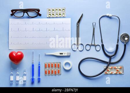 Doctor table with medical items and pills on blue background, top view Stock Photo