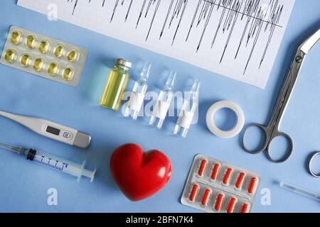 Doctor table with medical items and pills on blue background, top view Stock Photo