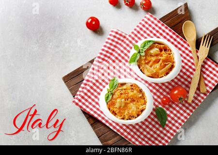 Delicious pasta Al Forno in bowls on napkin. Word ITALY on background. Italian food concept. Stock Photo