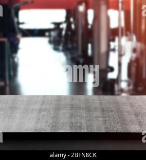 Wooden table against blurred gym interior background. Sport and healthcare concept. Stock Photo