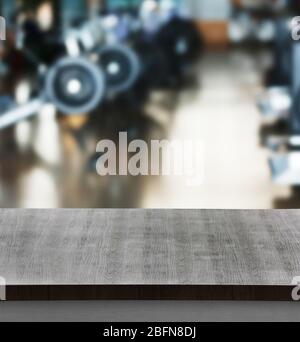 Wooden table against blurred gym interior background. Sport and healthcare concept. Stock Photo