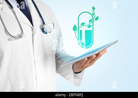 Doctor hand holding tablet with projection of pill. Alternative medicine concept. Stock Photo