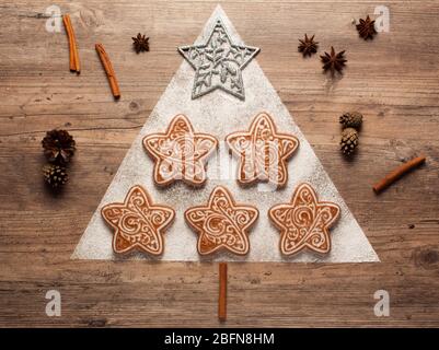 Christmas cookies and cookie cutters on wooden background. Christmas composition. Winter, new year concept. Flat lay, top view. Cones, cinnamon and co Stock Photo