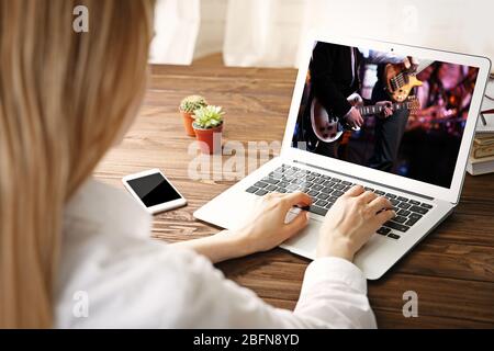Woman watching musical performance online on laptop. Video call and chat concept. Stock Photo