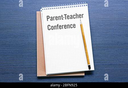 Text PARENT-TEACHER CONFERENCE written in notebook. Blue wooden background. School concept. Stock Photo