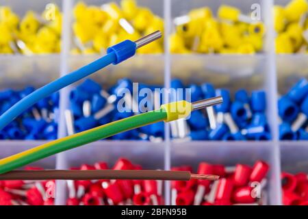 Colorful insulated crimp ends of power cables or brown stripped copper wire. Crimped connector electric joins. Ferrule pin cord terminals in toolbox. Stock Photo