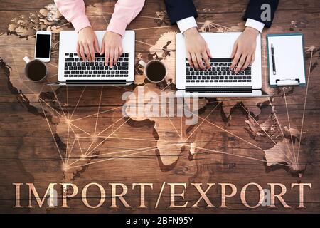 Text IMPORT/EXPORT on wooden background. People working at table, closeup. Business concept. Stock Photo