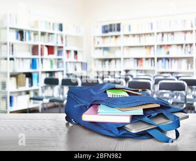 Backpack with stationery and laptop on table at library Stock Photo
