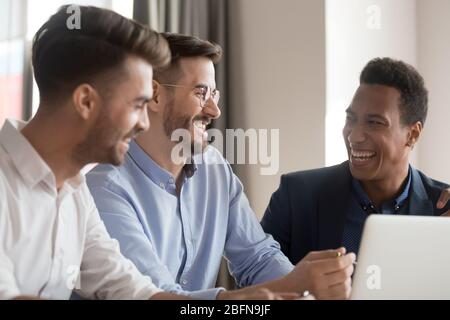 Diverse colleagues having fun telling anecdotes joking at workplace Stock Photo