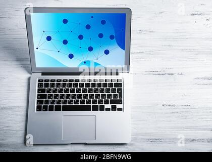 Laptop on white wooden background. Network design on screen. Stock Photo