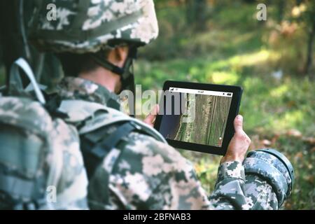 Soldier using map on tablet for orientation at forest Stock Photo