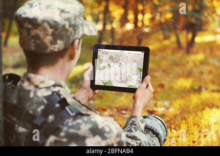 Soldier using map on tablet for orientation at forest Stock Photo