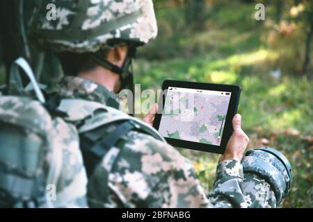 Soldier using map on tablet for orientation at forest Stock Photo