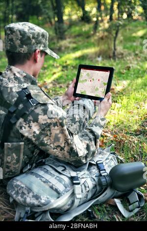 Soldier using map on tablet for orientation at forest Stock Photo