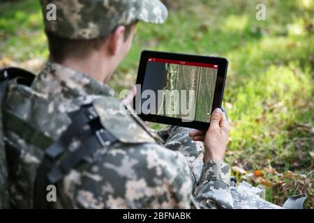 Soldier using map on tablet for orientation at forest Stock Photo