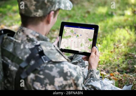 Soldier using map on tablet for orientation at forest Stock Photo