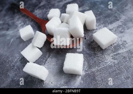 Close up a sugar cubes on wooden spoon on the table. Stock Photo