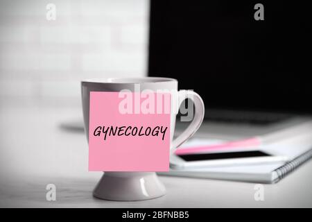Note paper with written word GYNECOLOGY on cup. Health care concept. Stock Photo