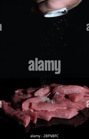 Hand pepper raw pieces of meat. Cooking at home, in the restaurant. Ingredients for the recipe. menu, chef Stock Photo