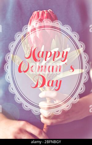 Text HAPPY WOMAN'S DAY on background. Woman holding beautiful flower, closeup Stock Photo
