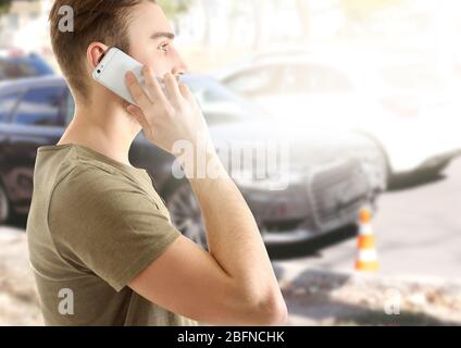 Young man talking on phone after car accident. Traffic safety concept. Stock Photo