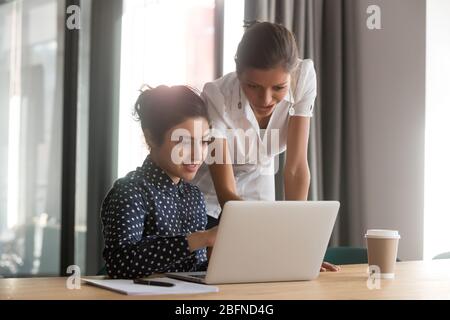 Diverse associates working together using laptop corporate application Stock Photo