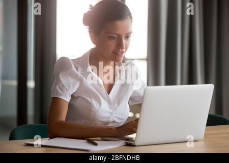 Businesswoman sitting at office desk typing on computer Stock Photo