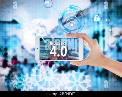 Female hand with smartphone on cityscape background. Text INDUSTRY 4.0 on screen Stock Photo