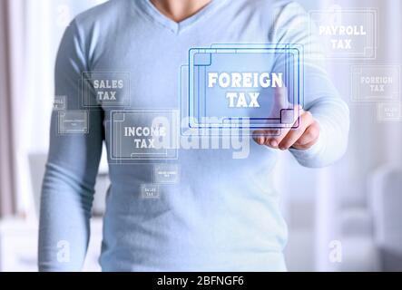 Man pushing FOREIGN TAX button on virtual screen. Taxation concept Stock Photo