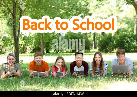 Young people using modern devices for studying outdoor. Text BACK TO SCHOOL on background Stock Photo