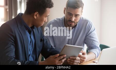 Multi-ethnic business partners discuss project using tablet device Stock Photo