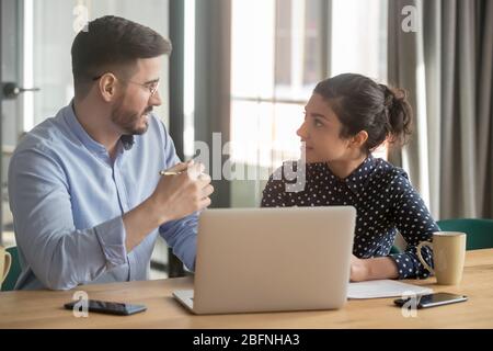 Multi-ethnic co-workers discuss project sitting at workplace Stock Photo