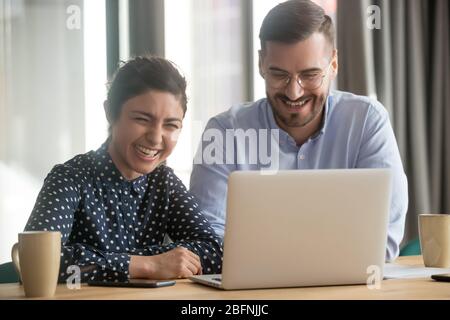 Diverse coworkers sitting at desk joking in the workplace Stock Photo