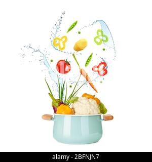 Different vegetables, water splashes and saucepan on white background Stock Photo