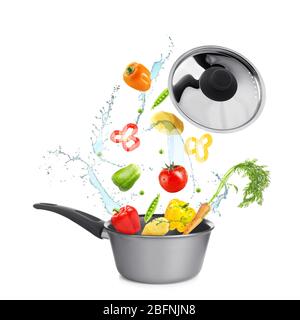 Different vegetables, water splashes and saucepan on white background Stock Photo