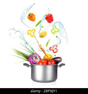 Different vegetables, water splashes and saucepan on white background Stock Photo