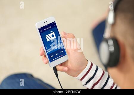 Man listening to radio on mobile phone indoors Stock Photo
